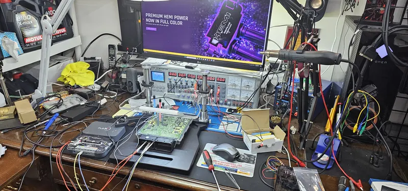 ECU opened on the electronics bench — programmer, probes, bench power