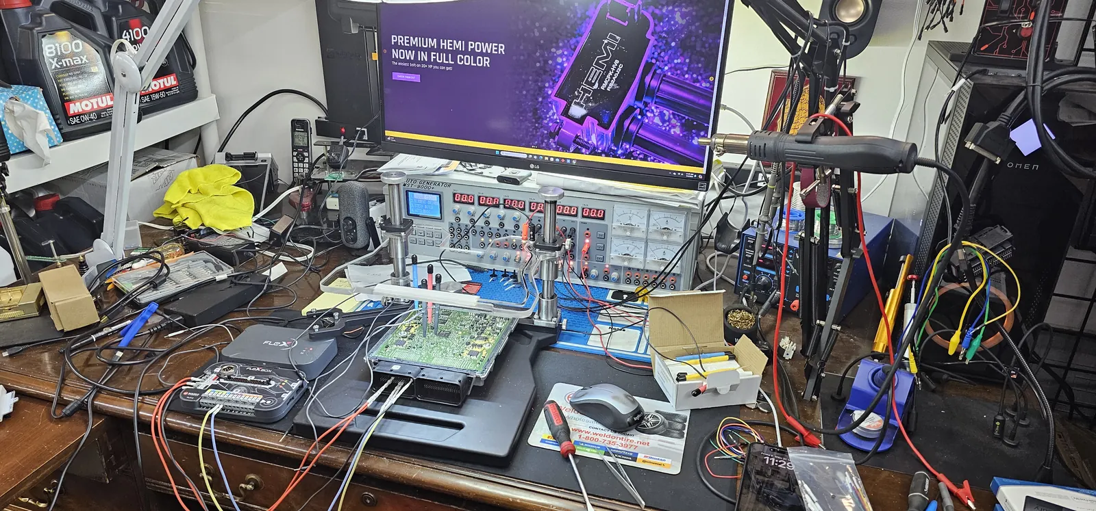 ECU opened on the electronics bench at Prestige Performance Center — bench power supply, programmer and probes on the board