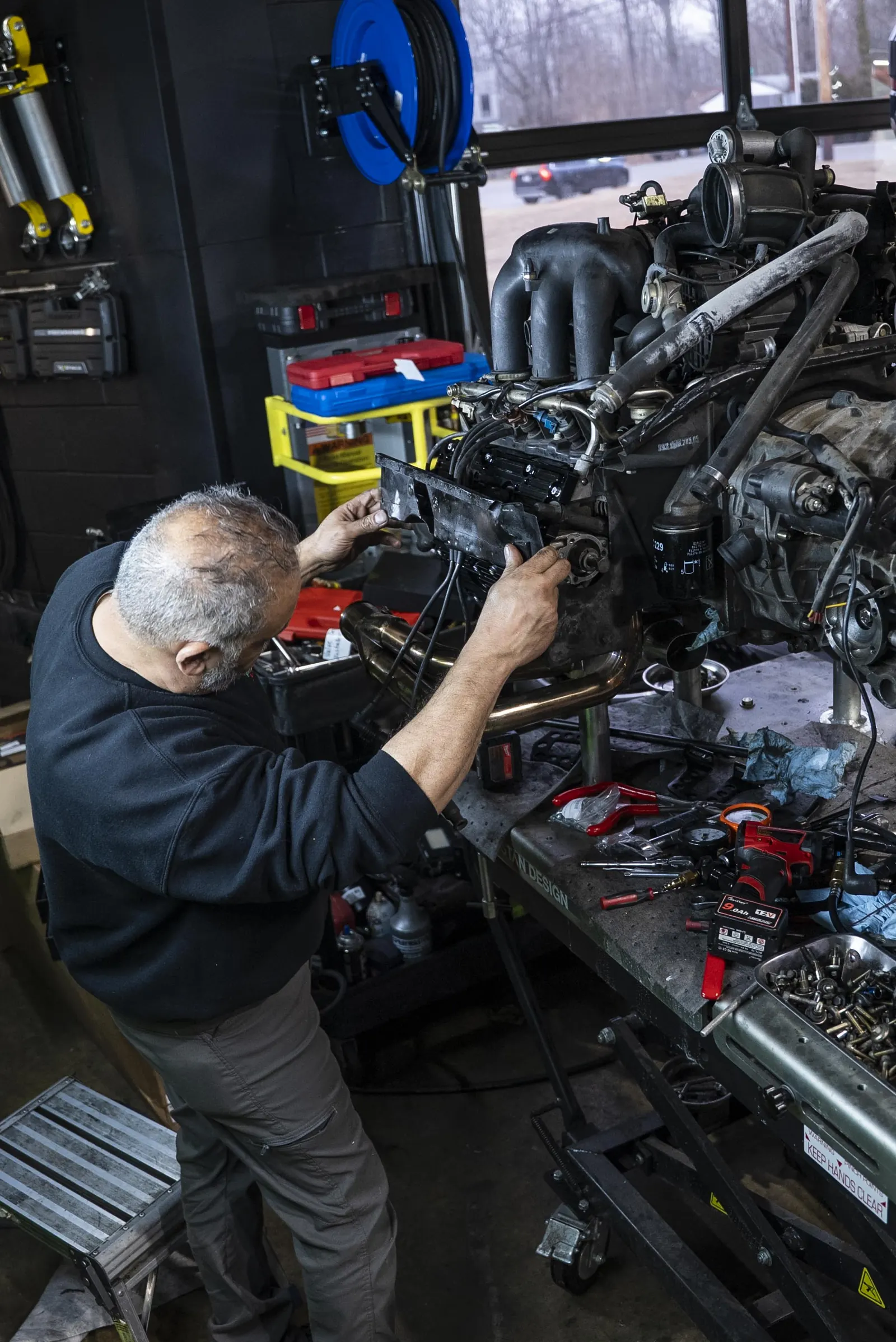 Technician working over a flat-six engine on the build bench