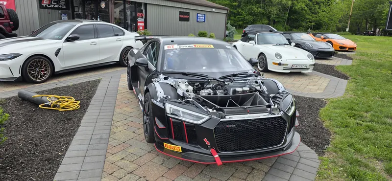 Race prep out front — GT4 with the nose off, air-cooled 993 and GT3 behind