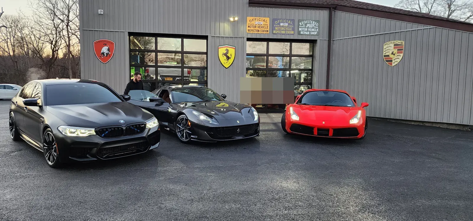 BMW M5 and two Ferraris lined up in front of Prestige Performance Center — the caliber of work waiting in the bays