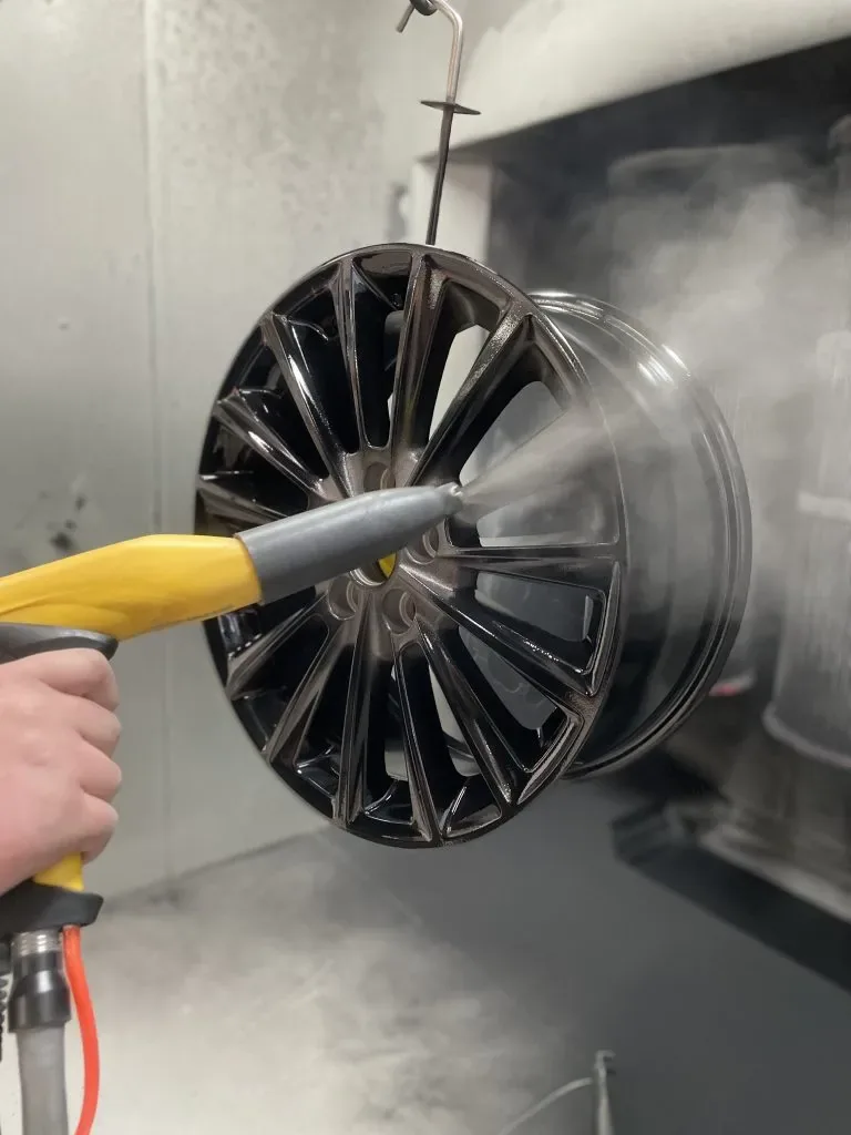 Powder coating a wheel in the booth at Prestige Performance Center
