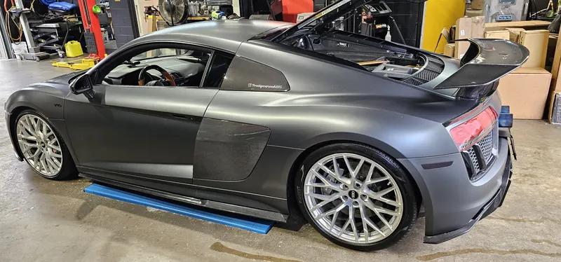 The shop R8 with the engine bay open — carbon wing and gold accents