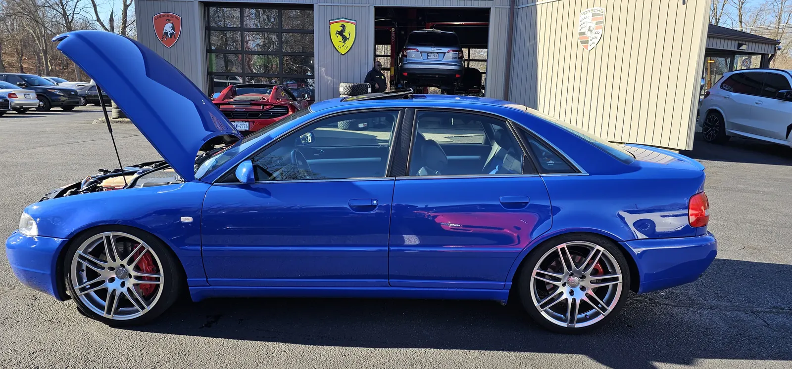 Nogaro blue B5 Audi S4 at Prestige Performance Center, hood up for twin-turbo service