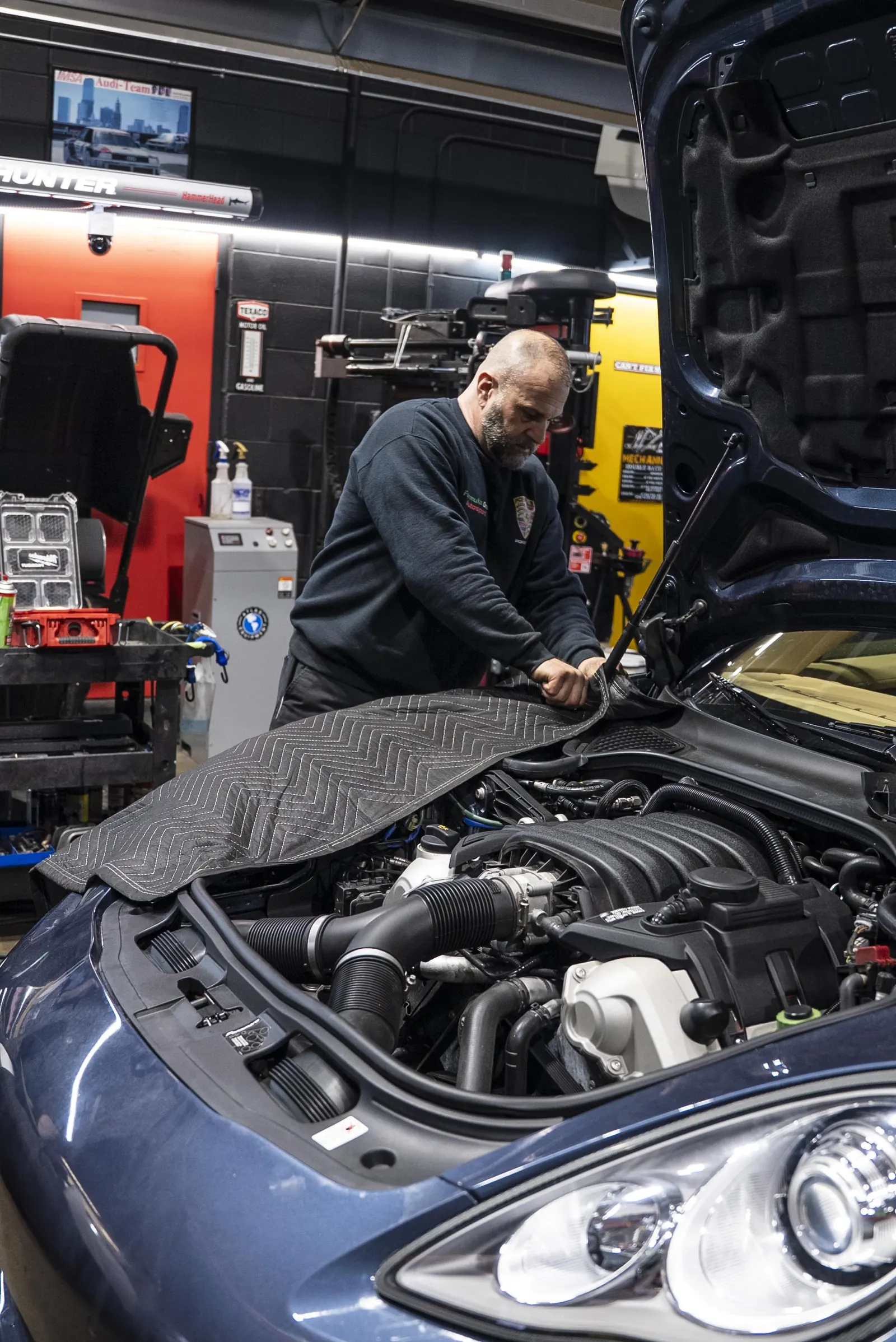 Technician prepping a Porsche Panamera in the Prestige Performance Center service bays
