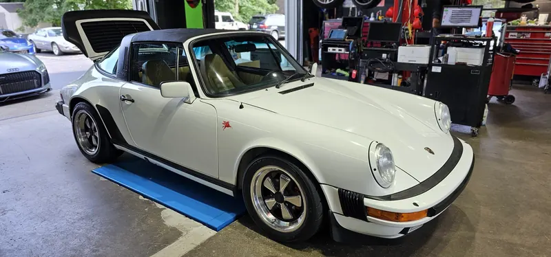 White 911 Targa front quarter with the shop R8 behind