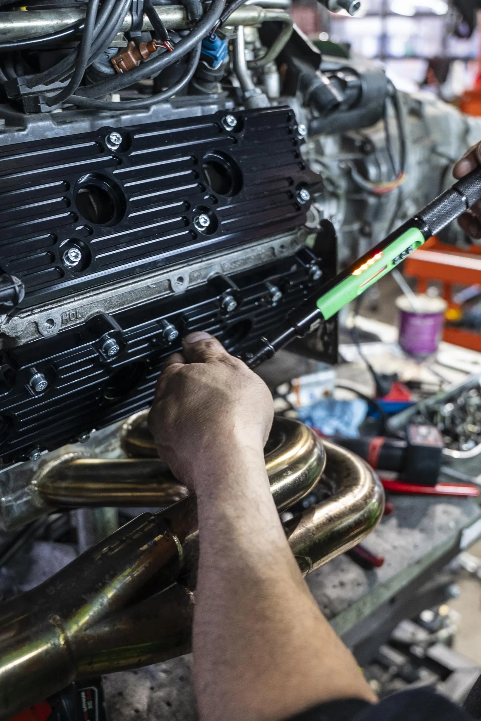 Technician torquing valve cover fasteners with digital verification on a Porsche flat-six